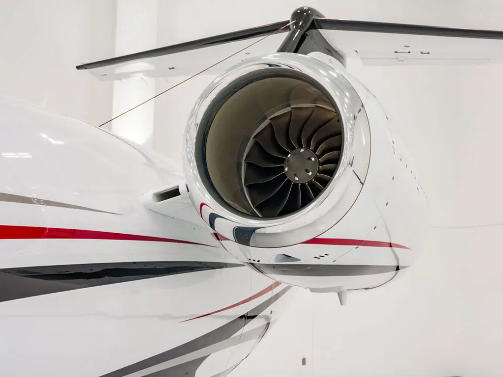 A close-up view of the polished engine intake and fan blades on the tail-mounted engine of a Cessna Citation Latitude.