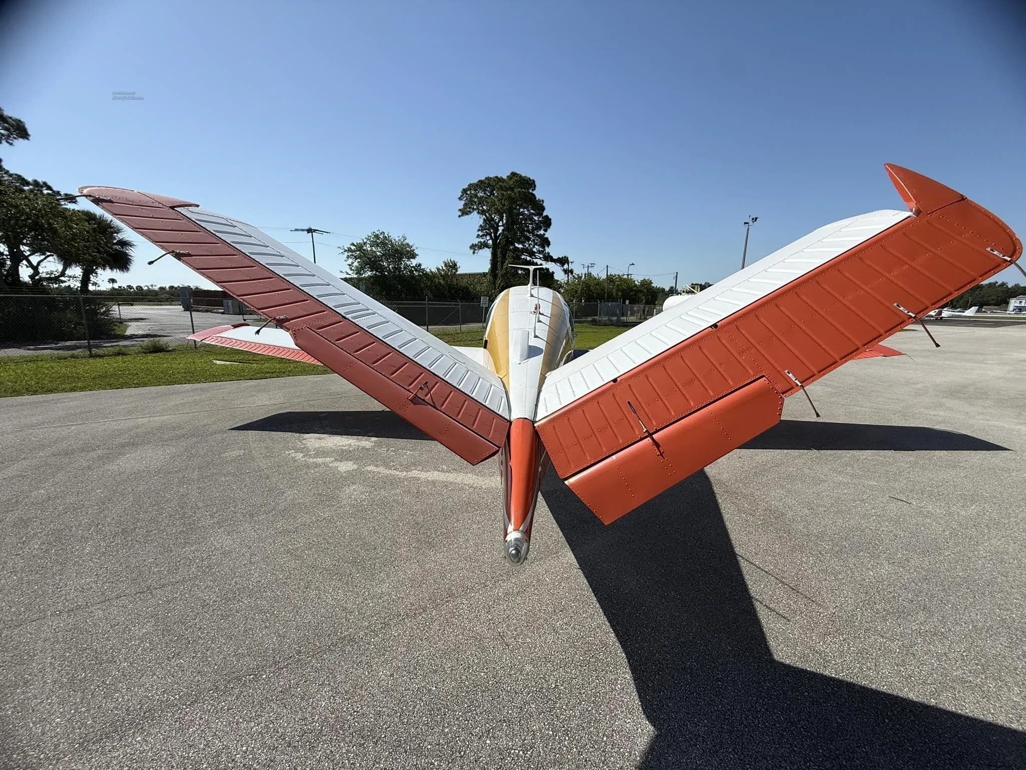 A rear view of a white and orange single-engine aircraft, N2040Y, with its wings folded upwards.