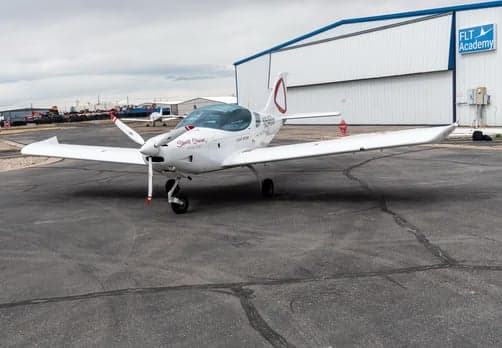 Side view of a white single-engine aircraft parked on the tarmac.