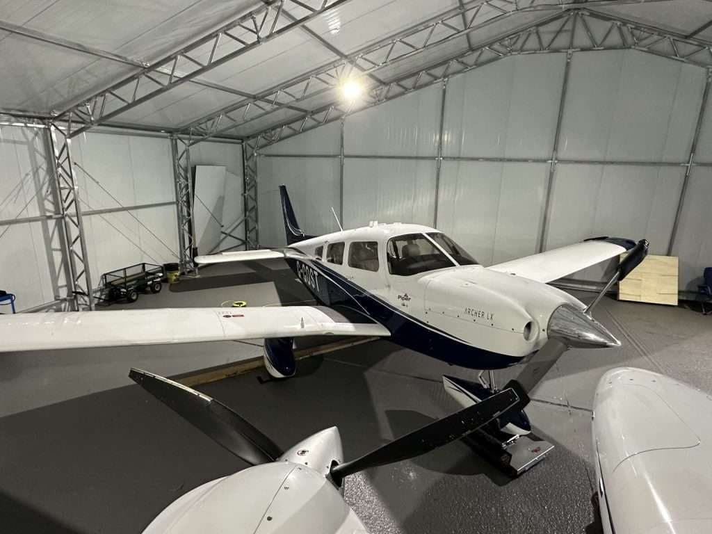 A Piper Archer LX aircraft is parked inside a hangar.