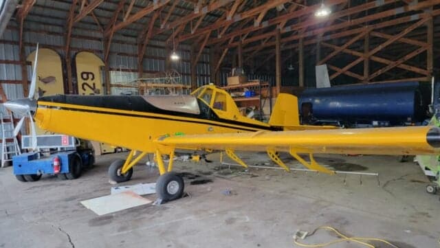 A yellow and black Air Tractor AT-400 sits inside a hangar.
