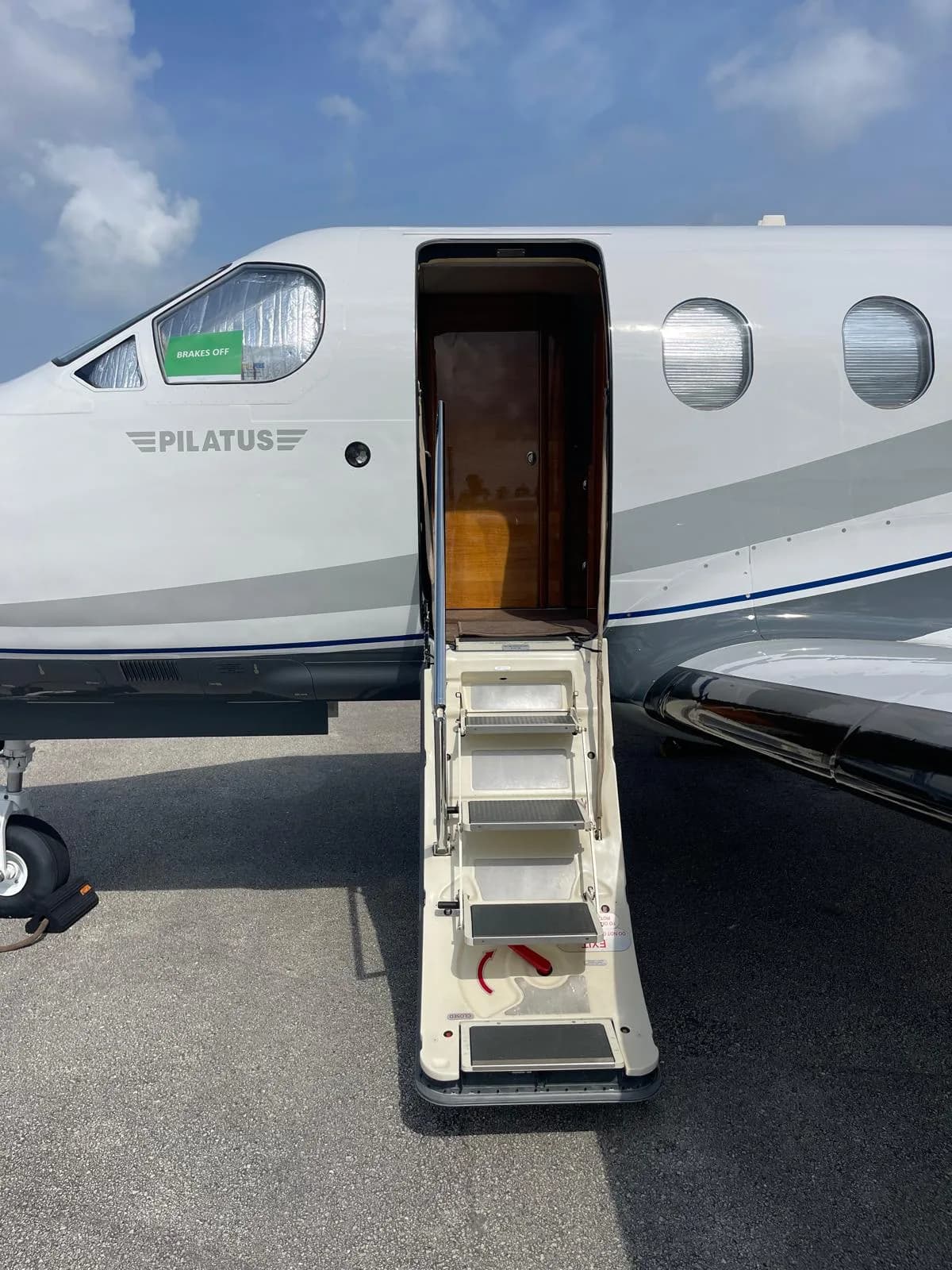 The open airstair door of a white Pilatus PC-12 NG aircraft, showing the steps leading into the cabin.