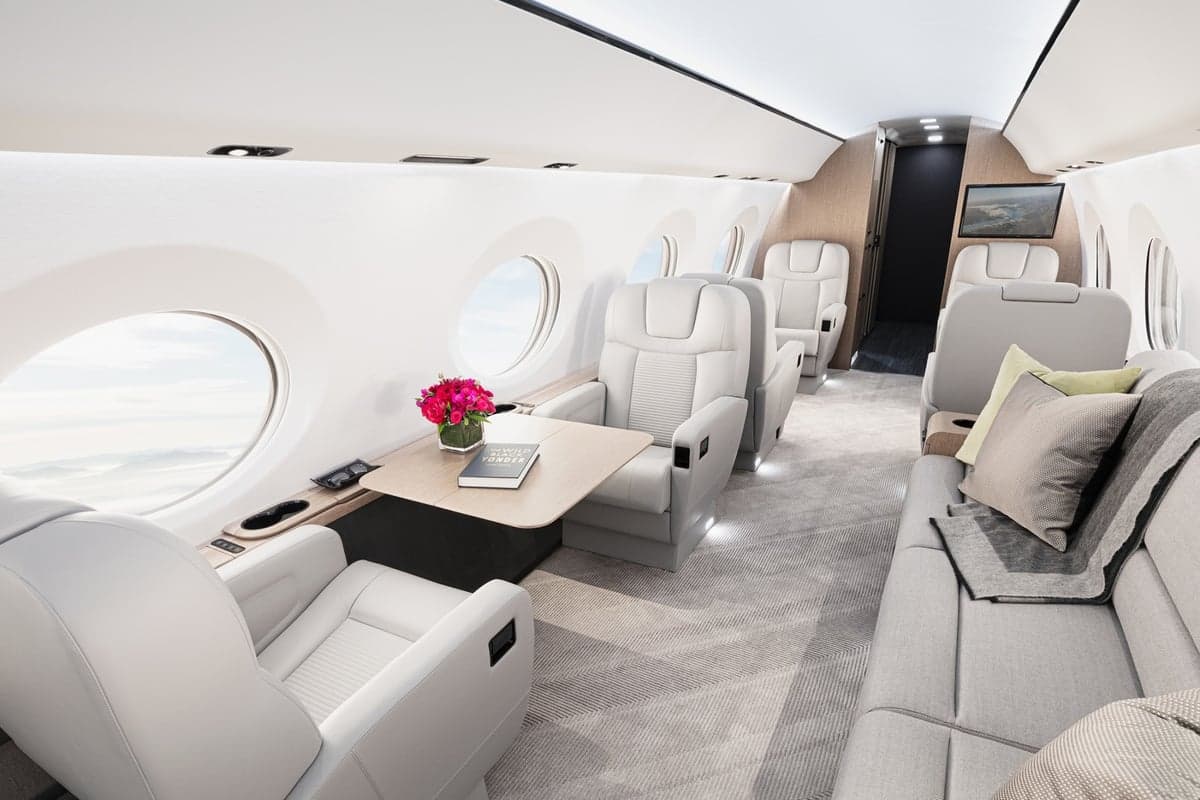 A luxurious aircraft interior with white leather seats and a small table.