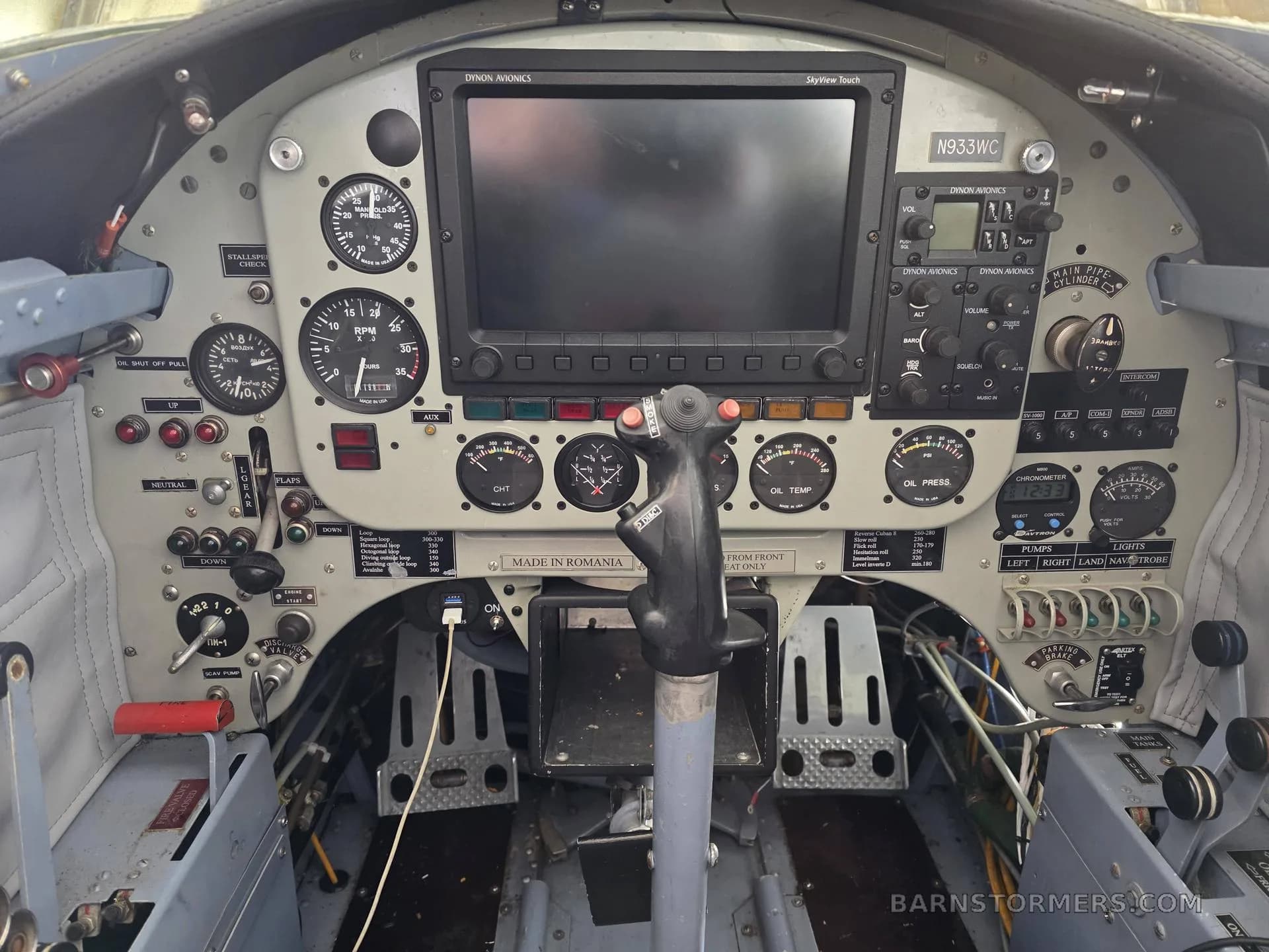 The front cockpit of a Yakovlev Yak-52, showing the instrument panel with a large Dynon SkyView display, traditional gauges, and a central control stick.