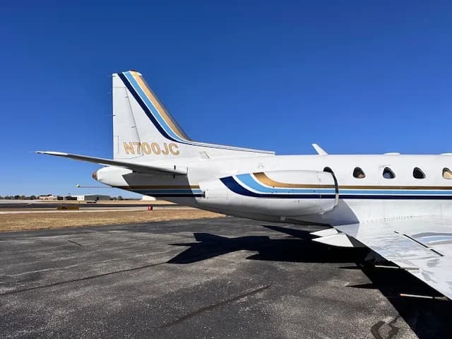 A close-up view of the tail section of the N700JC business jet, showing the blue and gold stripe livery and engine nacelle.