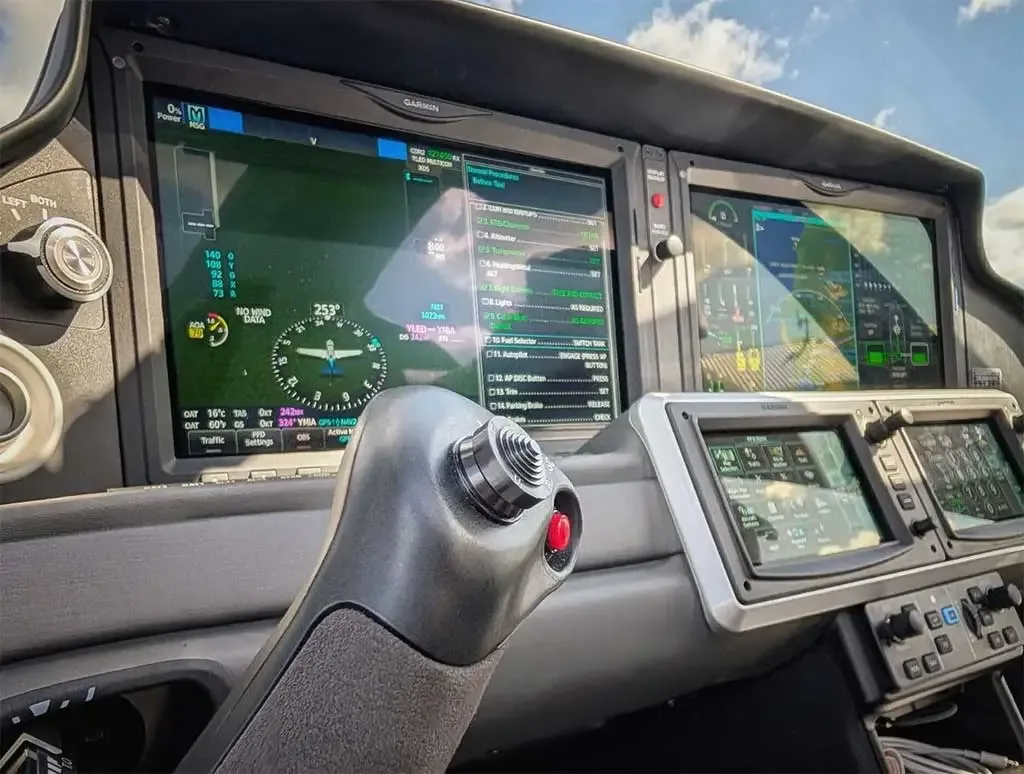 The modern glass cockpit of a Cirrus aircraft, featuring multiple Garmin displays and a side-stick control.