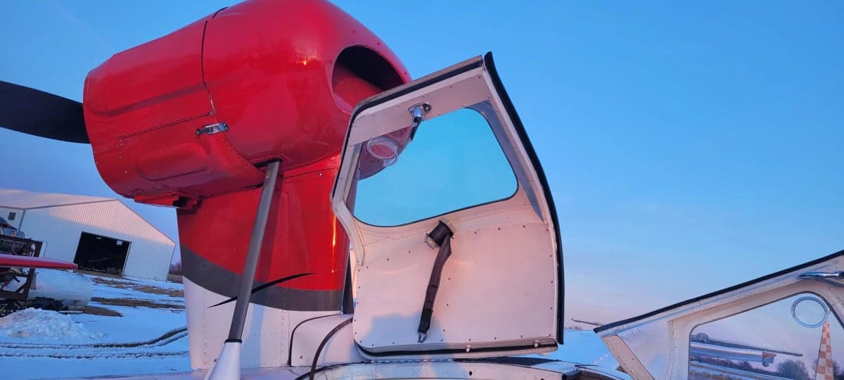 A close-up of the aircraft's open door and red engine cowling.