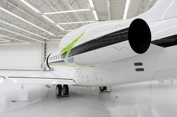 Close-up of the tail section of a white jet with green accents.