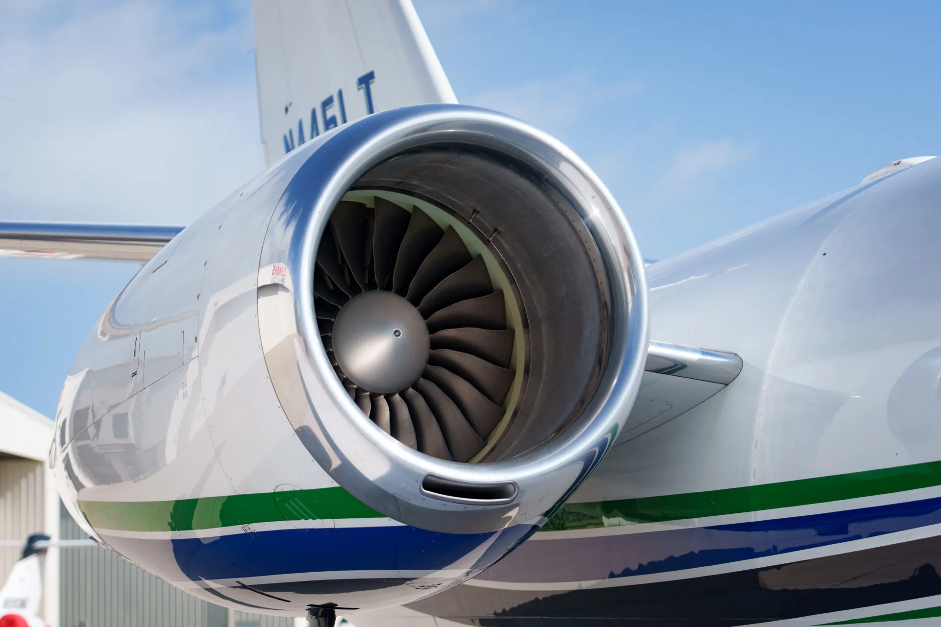A close-up view of the polished engine intake and fan blades of a white business jet.