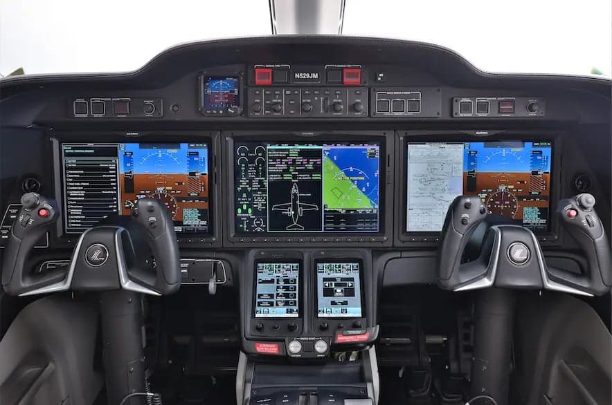 A close-up view of the HondaJet HA-420 cockpit's glass panel displays showing flight information and navigation.