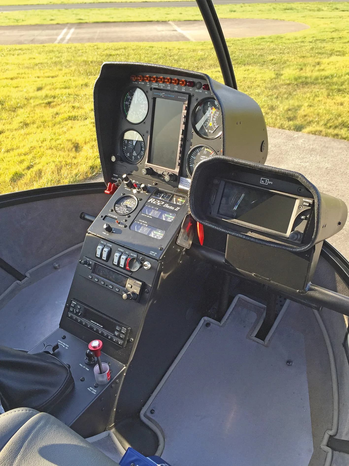The instrument panel and controls of a Robinson R22 Beta II helicopter are visible.