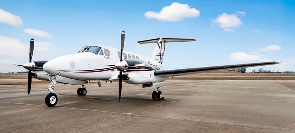 A Beechcraft King Air 200 on the ramp with a white and black paint scheme.