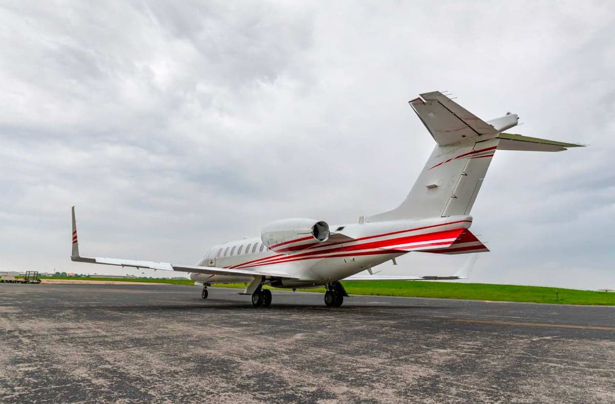 Rear view of a Learjet aircraft with red stripes parked on the tarmac.