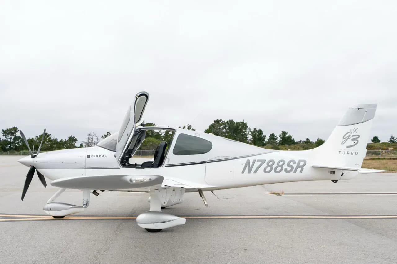 A white and grey Cirrus SR22 G3 Turbo aircraft, N788SR, with its doors open, parked on an airfield.