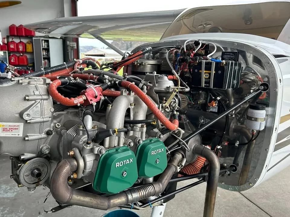 A detailed view of the Rotax engine of the Sirius LightSport aircraft with the cowling removed, showing internal components.