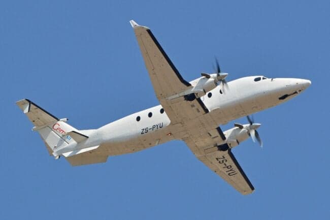 A white Beechcraft 1900C with registration ZS-PYU in flight.