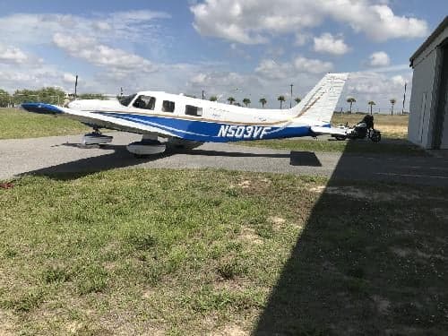 A Piper PA-28-181 Archer II aircraft with registration N503VF parked on the tarmac next to a hangar.