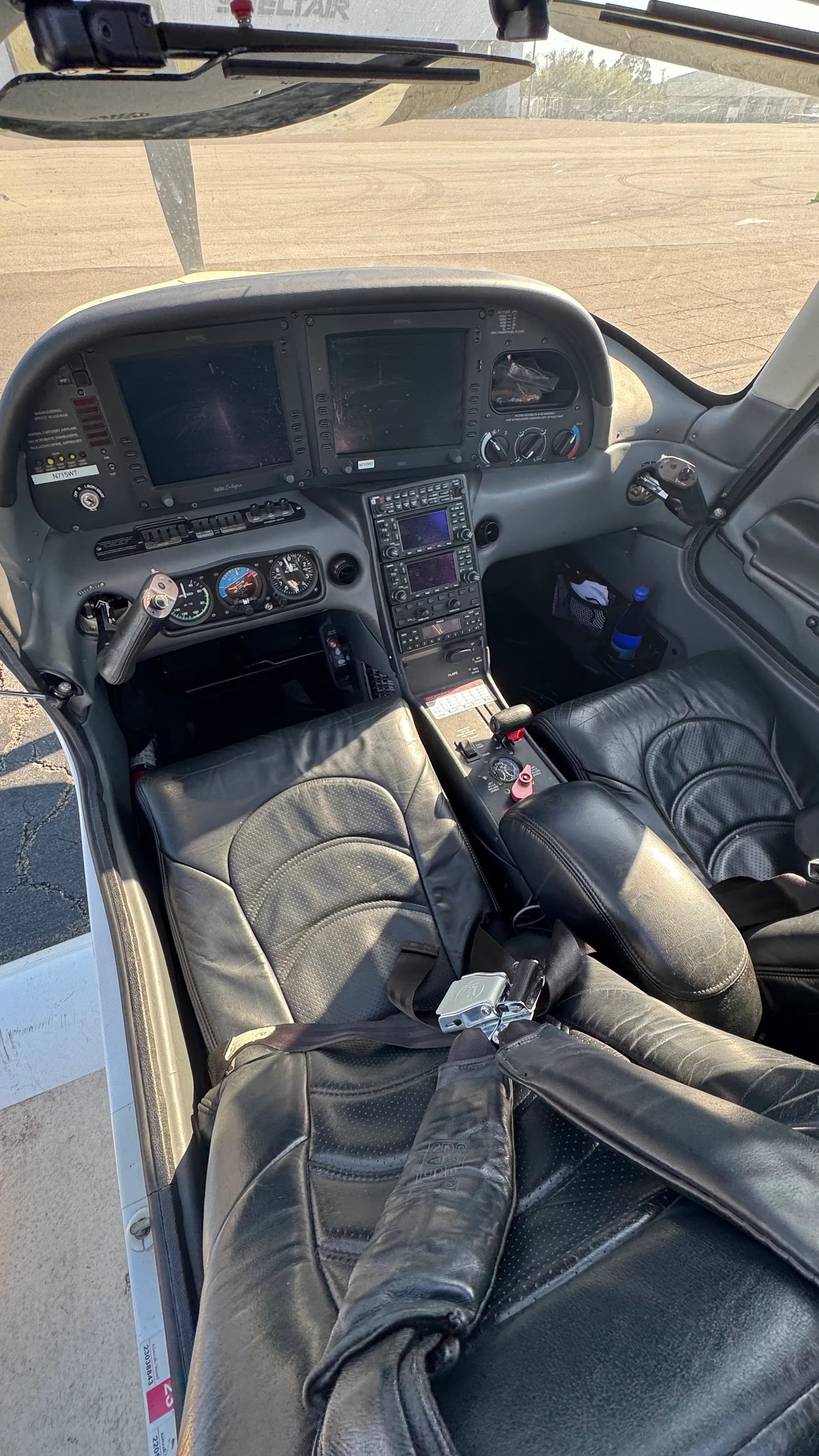 A view of the Cirrus SR22T cockpit showing black leather seats and the instrument panel with multiple screens.