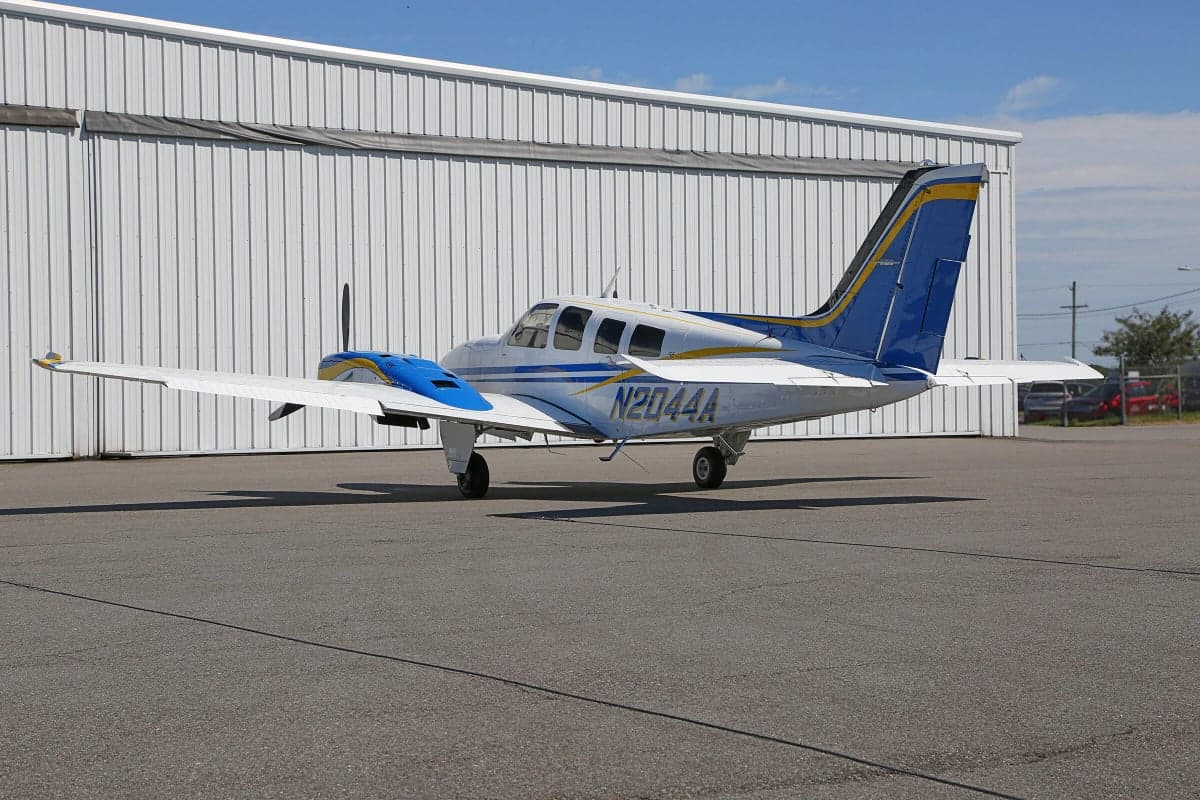 Side view of a Piper PA-31 Navajo Chieftain aircraft with registration N2044A parked on the tarmac in front of a hangar.