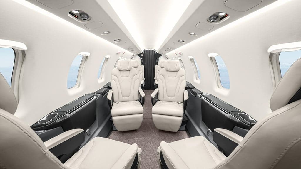 The luxurious interior cabin of a business jet with cream leather seats.