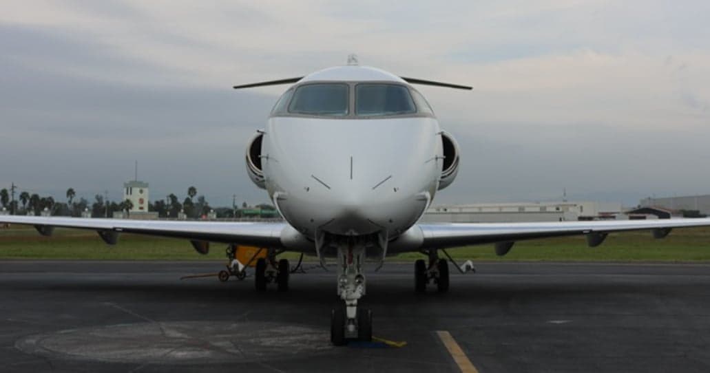 Front view of a white jet aircraft on the tarmac.
