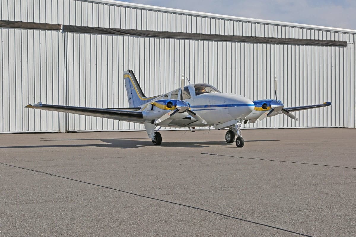 A Piper PA-31 Navajo Chieftain aircraft parked on the tarmac in front of a hangar.
