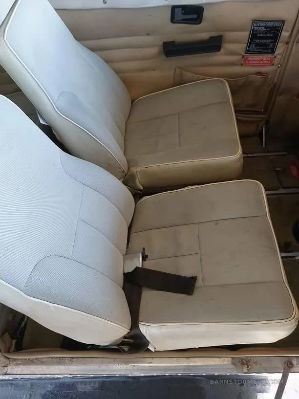 The light-colored rear passenger seats of a small aircraft cabin.