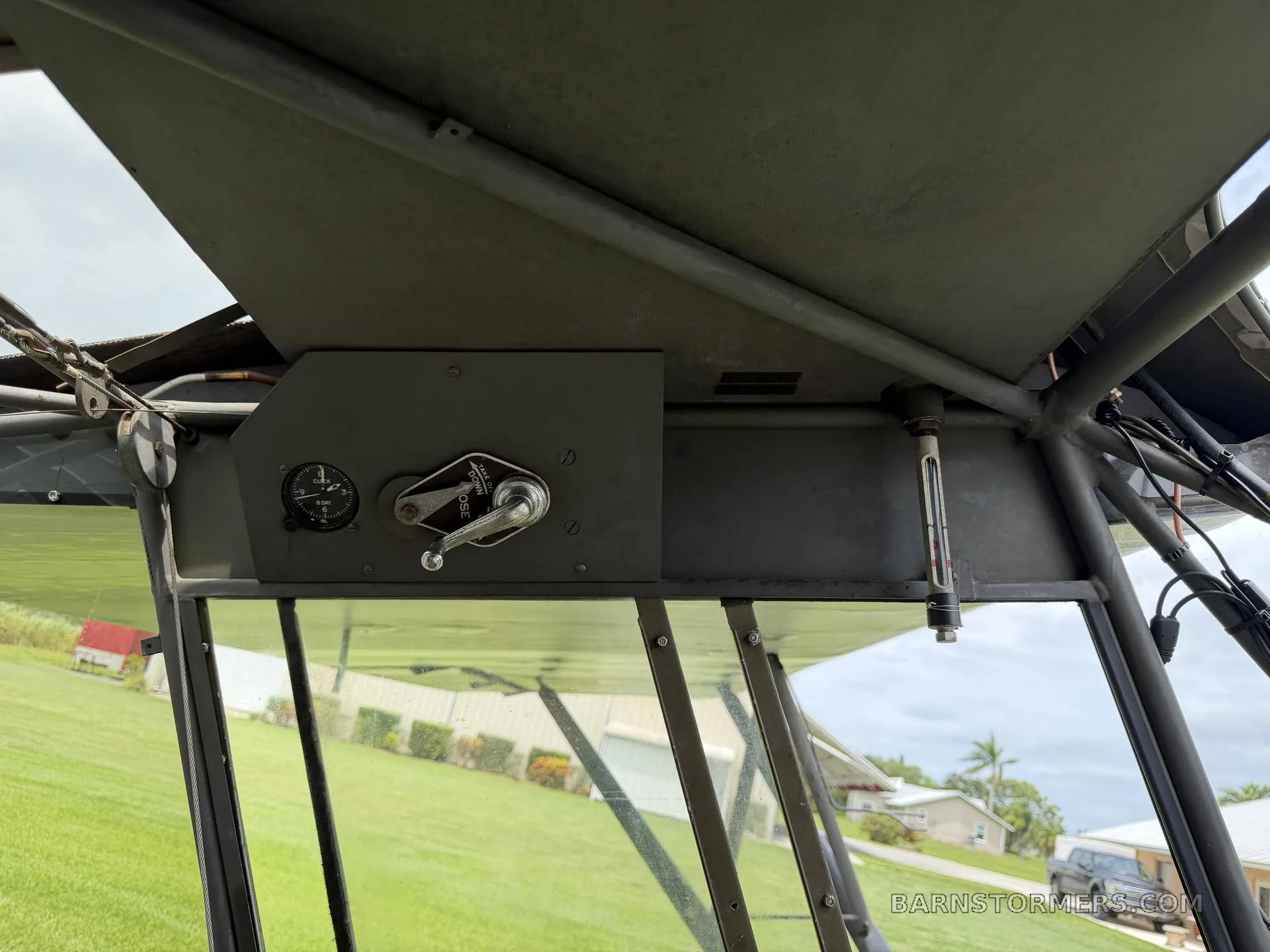 An overhead view of a control panel with a crank and gauge, located inside the aircraft's cabin structure.