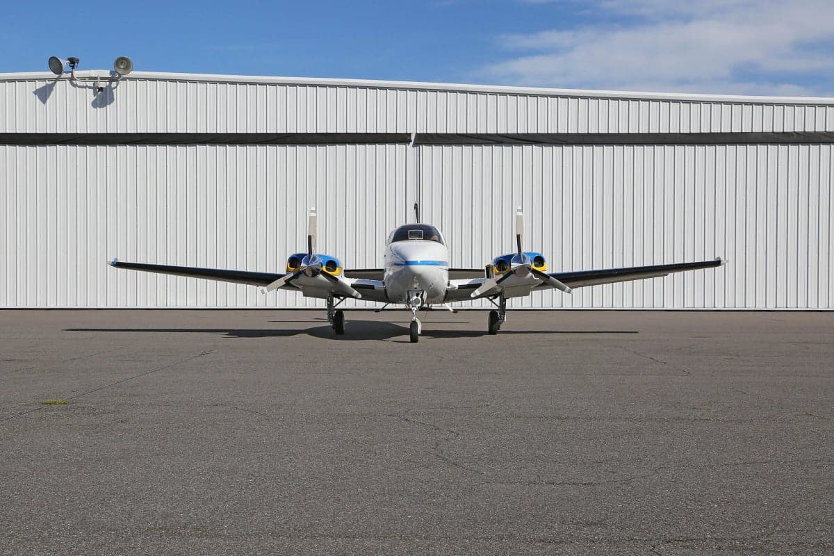 Front view of a Piper PA-31 Navajo Chieftain aircraft parked on the tarmac in front of a hangar.