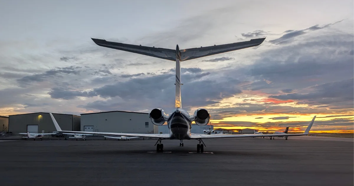 Rear view of a Gulfstream jet on the tarmac at sunset.