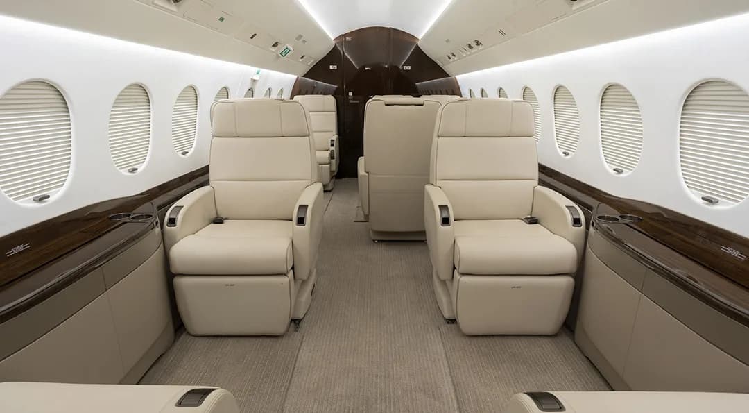 The aircraft interior features cream-colored leather seats and wood trim.