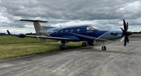 Pilatus PC-12 aircraft with a blue and silver paint scheme parked on the tarmac.