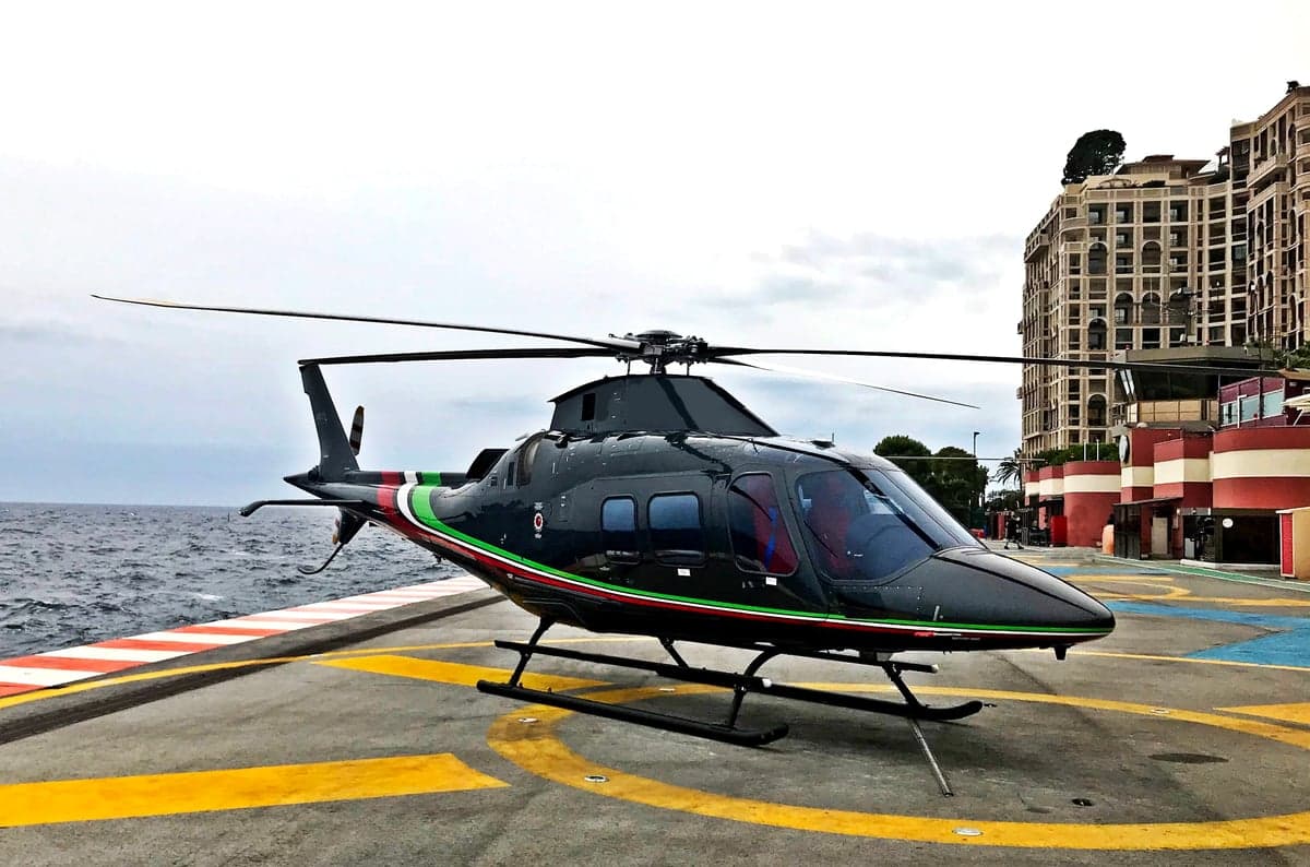 A black helicopter in flight against a blue sky.