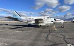 A Beechcraft Baron with a blue and white paint scheme parked on the tarmac.