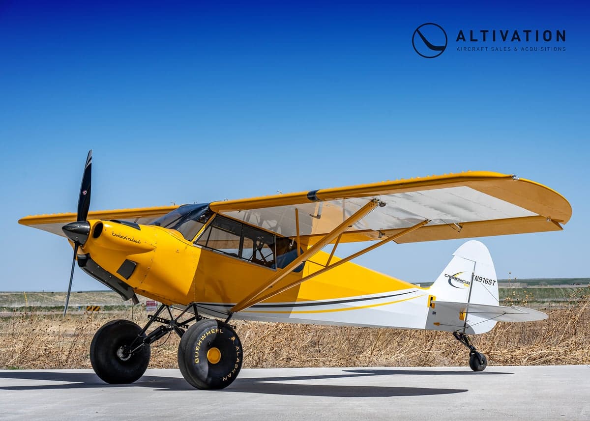A yellow and white Carbon Cub aircraft on the ground.