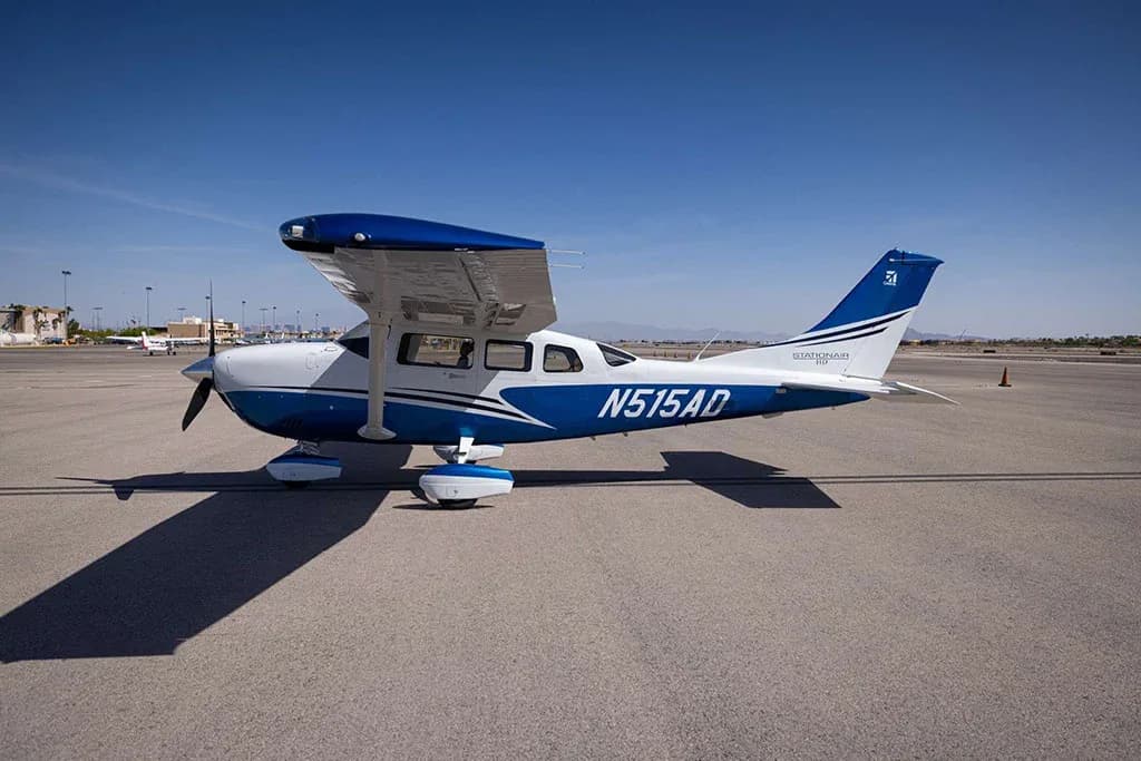 A side view of a white and blue Cessna Stationair N515AD parked on an airfield.