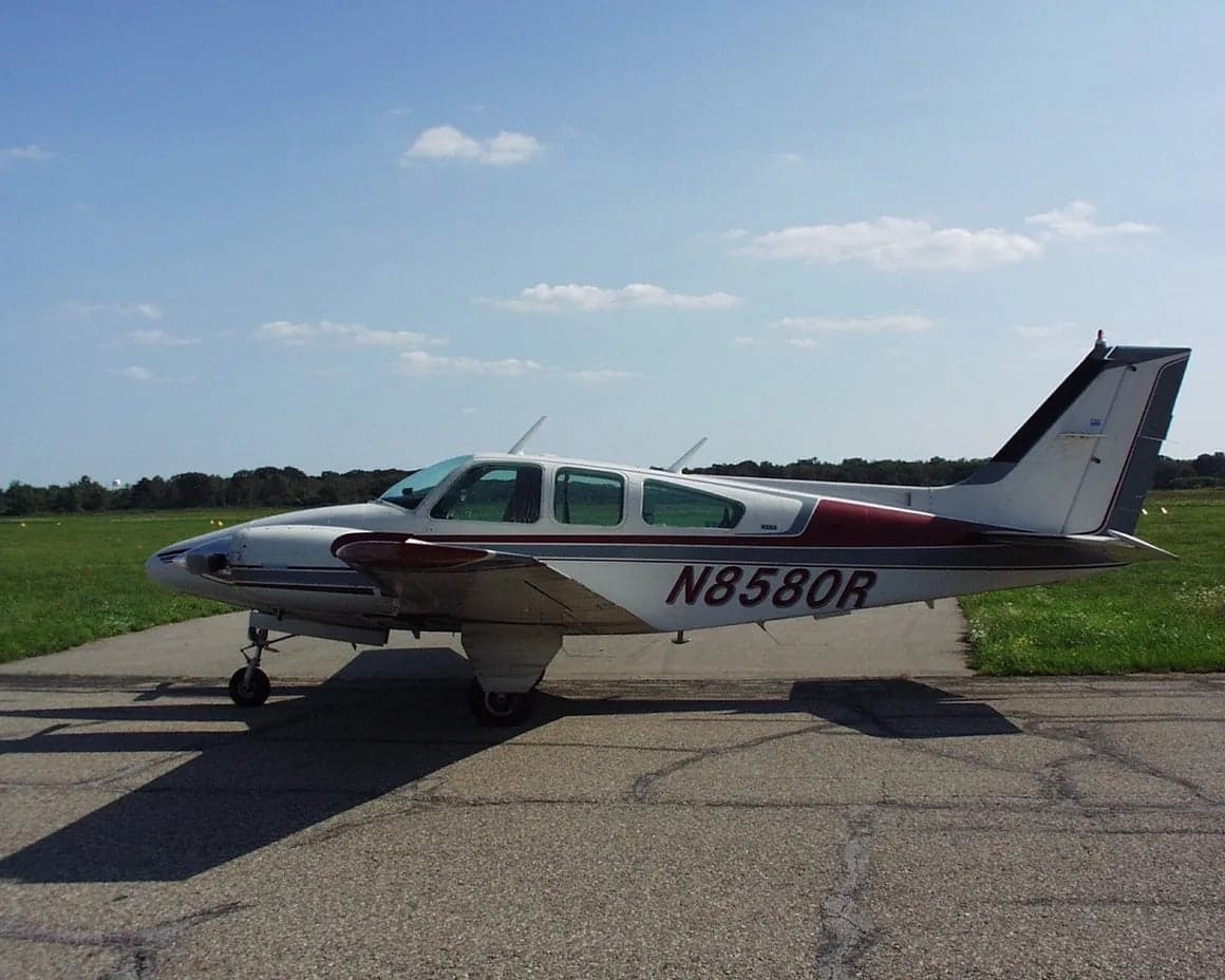 Side view of a white and maroon aircraft with tail number N8580R on a paved surface.