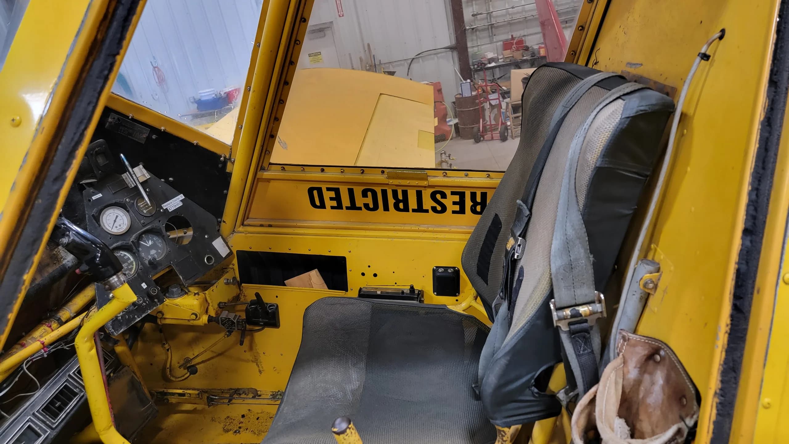 A view into the yellow aircraft's cockpit, showing the pilot's seat and a partial view of the instrument panel.