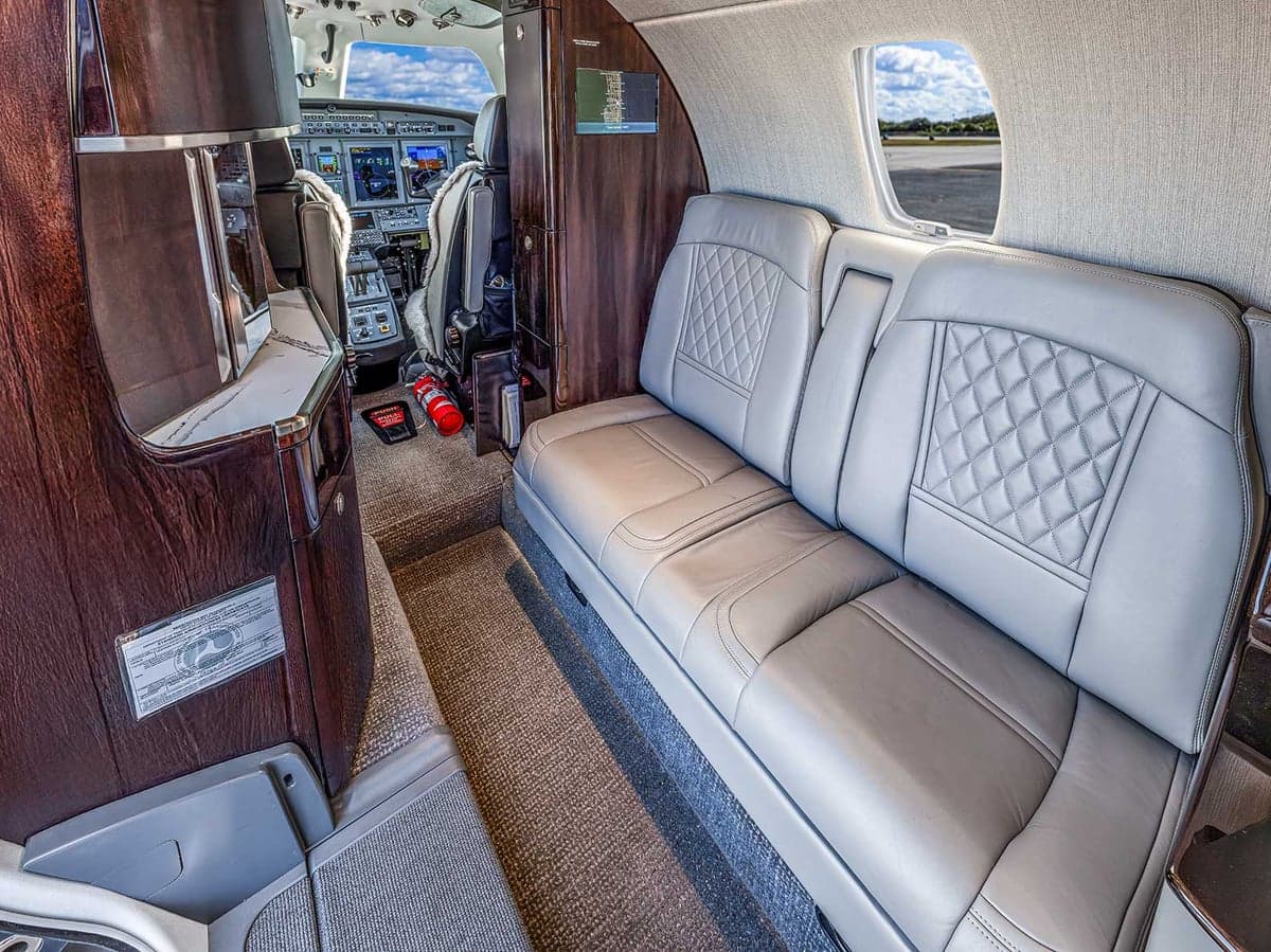 View of the Citation CJ4 cabin featuring gray leather seats and wood trim.