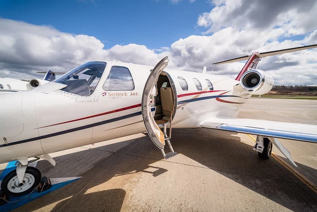 A close-up view of the front of a white Cessna Citation CJ1 with its main cabin door open and stairs extended.