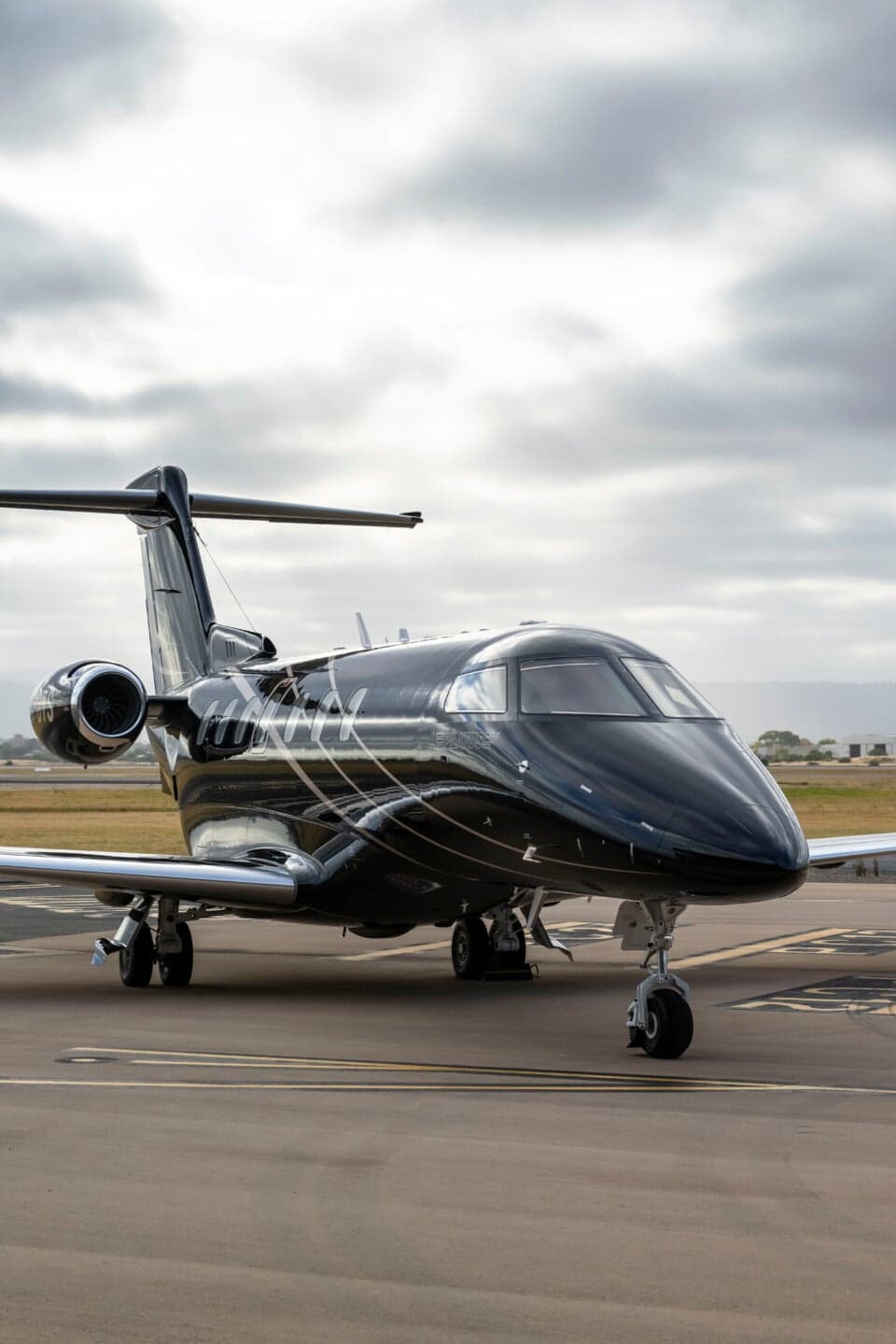 Side view of a black Pilatus PC-24 jet on the tarmac.