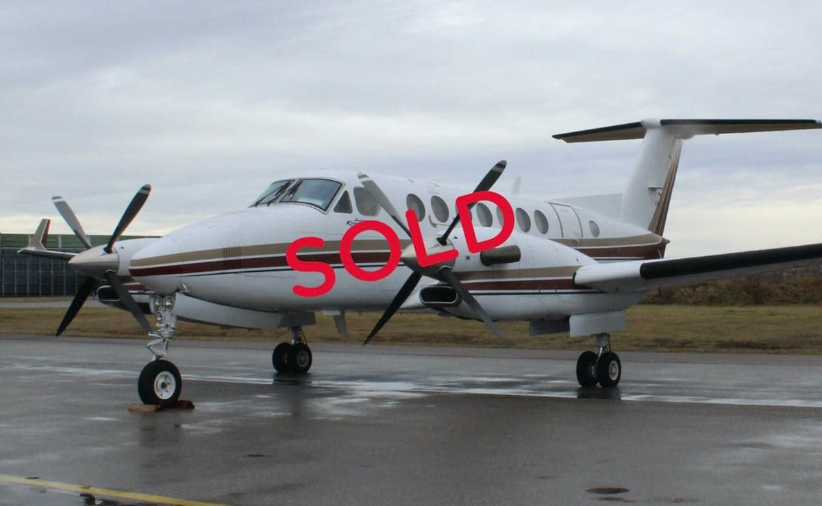 A King Air turboprop aircraft with a white and brown paint scheme is parked on the tarmac.