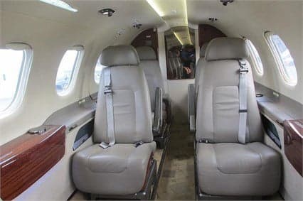 King Air cabin with gray leather seats and oval windows.