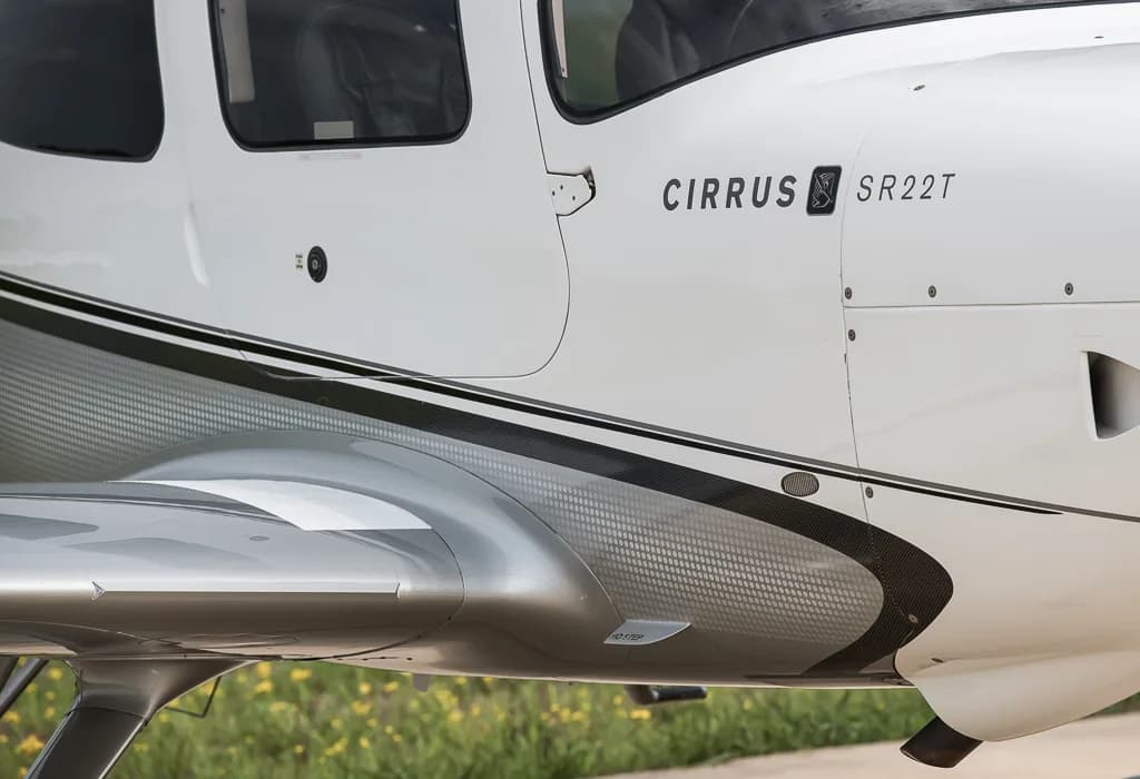 A close-up view of the fuselage of a Cirrus SR22T, showing the model designation and the silver and black striped paint scheme.