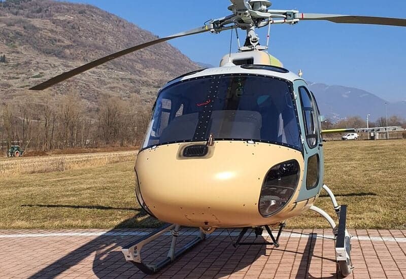 A close-up of the front of a Eurocopter AS350 Ecureuil helicopter with mountains in the background.