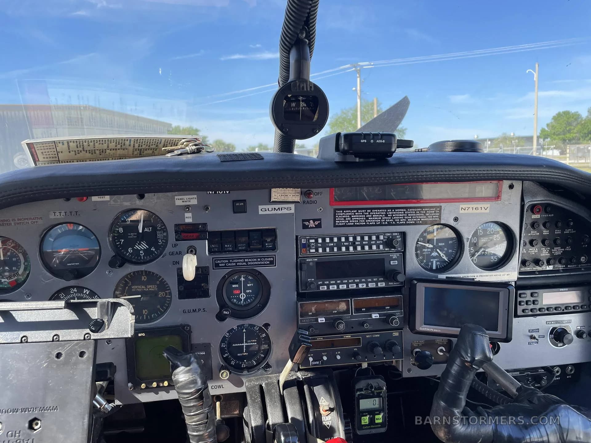 Close-up view of the aircraft's instrument panel, featuring analog gauges, radios, and a GPS unit, with the registration N7161V visible on the panel.