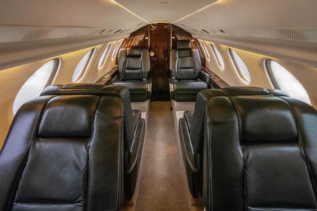 A wide view of the aircraft's elegant cabin interior, featuring multiple rows of black leather seats and overhead lighting.