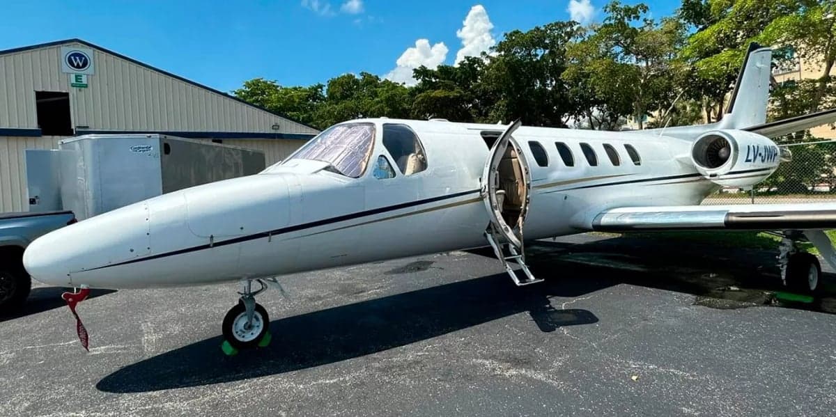 A Cessna Citation jet with an open door is parked on the tarmac.