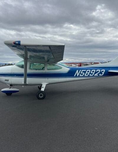 Side view of a Cessna 172 with a blue and white paint scheme on the tarmac.