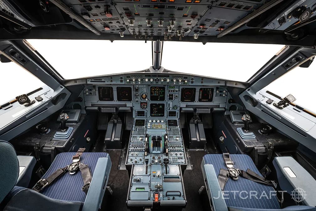 The cockpit of an Airbus A320 family aircraft with a clear view of the instrument panel and controls.